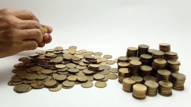 A man's hand takes coin from a pile of coins on the table. Coins with a denomination of 500 rupiah.