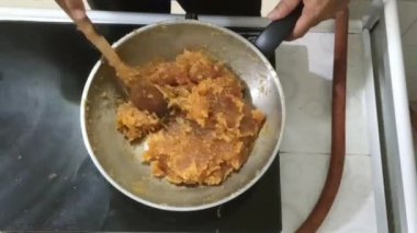 Geleneksel ananaslı pasta için düşük ısıda büyük bir tavada karıştırarak ananas reçeli pişirme işlemi yapıyor. Reçel, su buharlaşıp neredeyse kuruyana kadar pişirilir. buhar