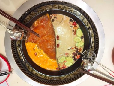 İki aromalı vegan Hotpot sosu, yani mantar, domates ve Yin Yang şeklinde bir kapta bulunan çeşitli sebze ve baharatlar. Hong Yun Hotpot, Pantai Indah Kapuk Jakarta.