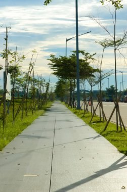 Mavi yaz gökyüzünde yoğun bulutların oluşturduğu bir arkaplan üzerine kurulmuş boş bir cadde. Güneşin altındaki bulutlu, parlak ve sakin yaz havası..