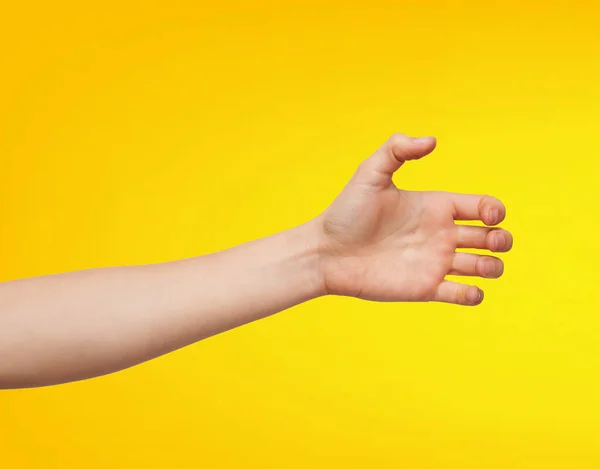 Close-up of an Asian man\'s hand in a grab pose, isolated on a yellow background.