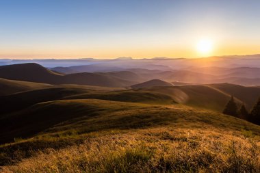 Gün batımında güneş ışınlarıyla dağlarda otlaklar.