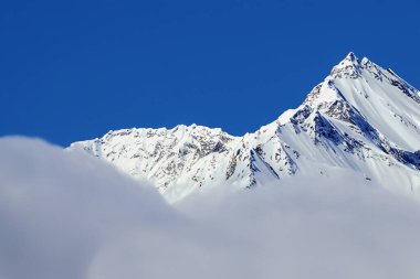 Açık mavi gökyüzü ile karlı dağ zirvesi. Kafkas Dağları, Gürcistan.