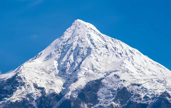 Snowy mountain peak with clear blue sky. Caucasus Mountains, Georgia.