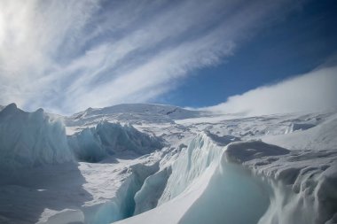 Karda buzdağı, mavi gökyüzüne karşı bulutlarla, Antarktika