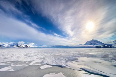Karla kaplı dağlar ve donmuş gölle güzel bir kış manzarası.