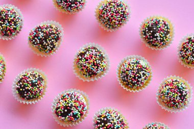 Çikolatalı keklerin düz bir fotoğrafı. Pembe kağıda serpiştirilip serpiştirilmiş..