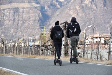 Çift bisiklet yolunda scooter sürüyor.