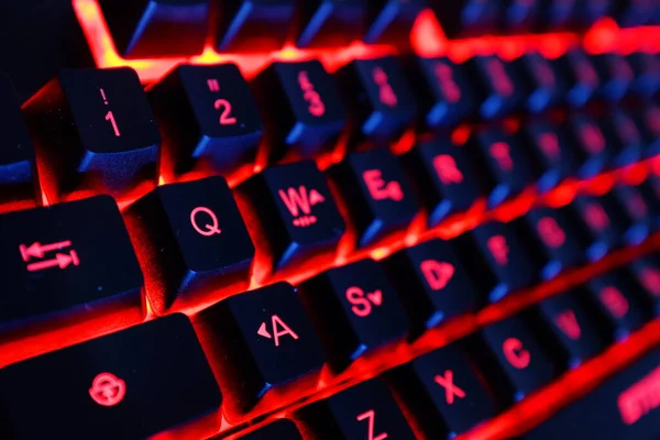computer keyboard with red neon light and dark background.