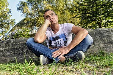 Parkta oturan yakışıklı, sıkılmış bir adamın portresi.