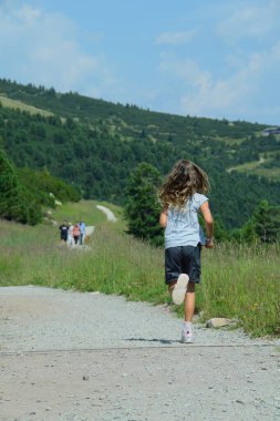 Küçük kız dağlarda koşuyor.
