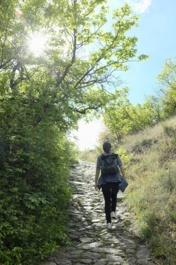 Güneşli bahar gününde yolda yürüyen bir kadın. 