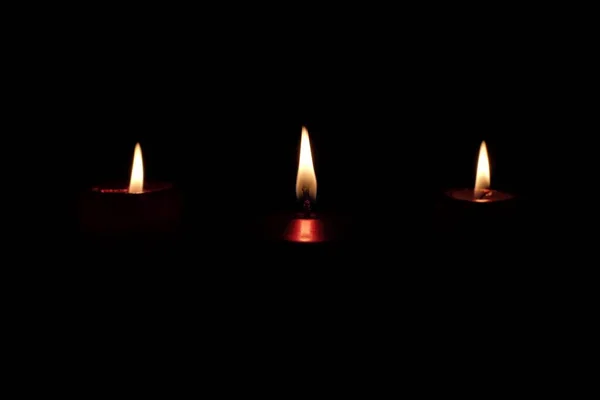 burning red candle isolated on black background