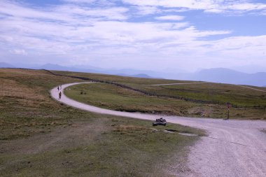 Bulutlarla kaplı yüksek dağ yolu ve uzaktaki insanlar