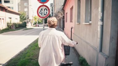 Son sınıf öğrencisi bir kadının el kamerasıyla şehirde yürüyen yolda bisikleti yuvarlarken çekilmiş..