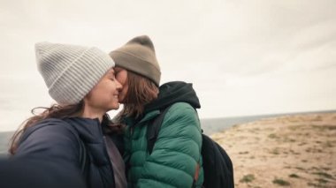 Mutlu lezbiyen bir çiftin kış denizinde selfie çekerken yavaş çekim görüntüleri..