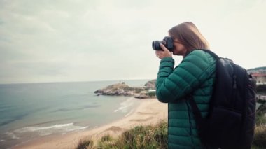 Bir kadın fotoğrafçının seyahat ederken deniz manzarasının fotoğraflarını çektiği yavaş çekim görüntüleri..
