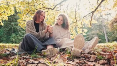 Romantik lezbiyen çift, güneşli bir günde sonbahar parkında sarılarak vakit geçiriyorlar..