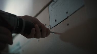A close-up shot of a person using a cordless screwdriver during renovation and home improvement.