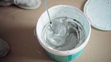 Close-up shot of a person mixing paint in the bucket with a cordless drill with a mixing nozzle.