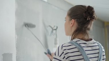 Duvarı silindirle boyayan genç bir kadının yavaş çekim görüntüsü..