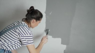 Duvarı yenilerken spatula kullanan beyaz bir kadının yakın plan fotoğrafı..