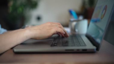Close-up shot of a persons hands typing on a laptop keyboard.