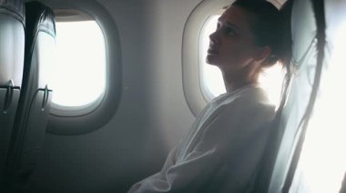 Genç bir kadın türbülans sırasında bir uçağın kabininde otururken endişelenir.