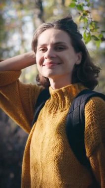 Sonbahar ormanında parlak sarı kazaklı güzel bir genç kadının portresi.