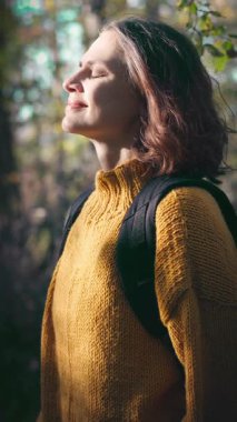 Sonbahar ormanında parlak sarı kazaklı güzel bir genç kadının portresi.