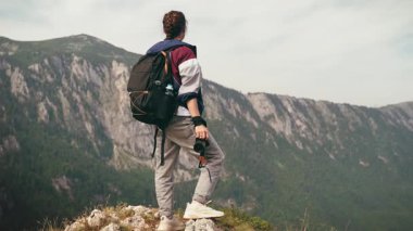 Profesyonel bir kadın fotoğrafçı, tek başına seyahat ederken dağın tepesinden çarpıcı bir manzara izler.