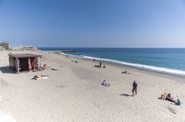 Sonbahar kışı. Güneşli bir günde az sayıda insanın olduğu terk edilmiş bir sahil..