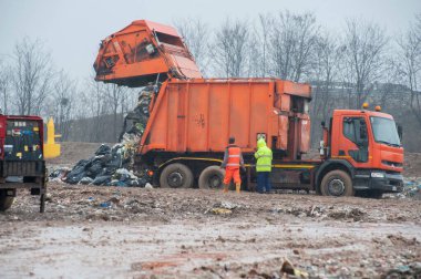 Belediye atıklarını boşaltın. Kamyon ve buldozerli işçiler atık depolama sahasında çalışıyor.