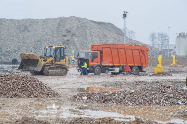 Belediye atıklarını boşaltın. Kamyon ve buldozerli işçiler atık depolama sahasında çalışıyor.