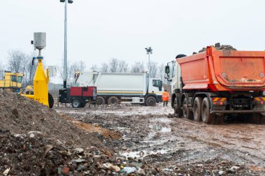 Dump municipal waste. Workers with trucks and bulldozers at work in waste storage landfill. clipart