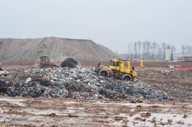 Dump municipal waste. Workers with trucks and bulldozers at work in waste storage landfill. clipart