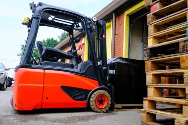 Forklift ön planda ahşap paletler ile ambarda ambalajlanmış paleti hareket ettiriyor