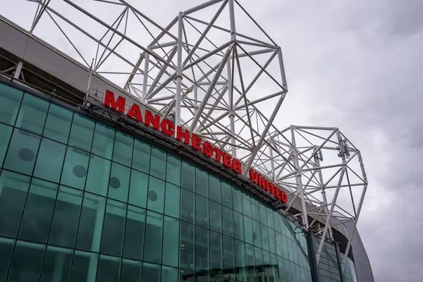 Manchester Trafford UK 29 Haziran 2024. Modern bir stadyumun dış görünüşü çarpıcı bir mimari ve bulutlu bir gökyüzünün altında cesur bir tabela..