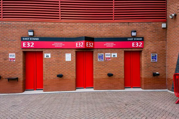 stock image Manchester Trafford UK 29 June 2024. Bright red stadium entrance gates labeled E32 on a brick wall, East Stand, minimalistic urban design.