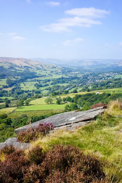 stock image Scenic countryside landscape with lush green fields and rolling hills under a clear blue sky. Hathersage moor Derbyshire UK.