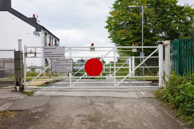 Astley Moss, Manchester, Uk, 09-08-2024: Closed railroad gate with warning signs barring entry to a railway track in a semi-rural area. clipart