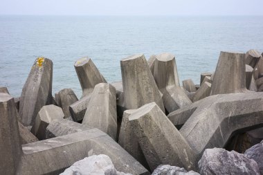 Sakin bir denize karşı kayalık bir sahil şeridinde deniz savunması beton tetrapodları, kıyı korumasını arttırır..
