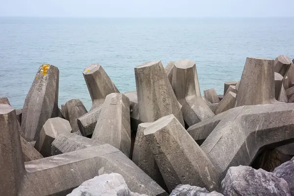 stock image Sea defense concrete tetrapods on a rocky coastline against a calm sea, enhancing coastal protection.