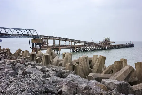 stock image Colwyn Bay, North Wales, UK, 09-08-2024. Long industrial pier extending into the sea on a cloudy day.