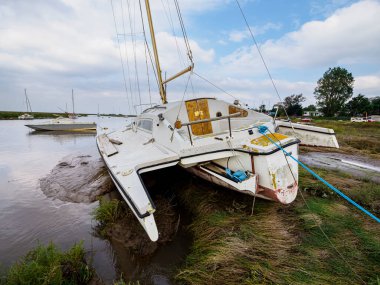 Heswall, Wirral, İngiltere. Sahilde terk edilmiş bir yelkenli, kısmen çamura batmış ve diğer teknelerle çevrili..