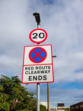 Traffic signs displaying a clearway indication and a 20 mph speed limit under a cloudy sky. clipart