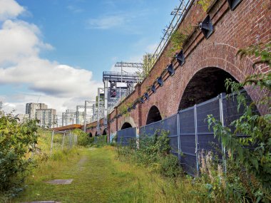 Eski tuğla tren kemerleri Salford, Manchester, bulutlu bir gökyüzünün altında yeşilliklerle çevrili..