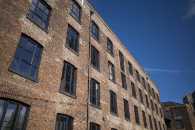 Tarihsel tuğla fabrikası açık mavi gökyüzüne karşı apartmanlara dönüştürüldü. Manchester, İngiltere.
