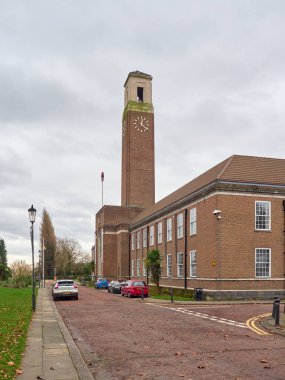 Swinton, Manchester, UK, 31-12-2024: Salford town hall Swinton. Brick building with clock tower under cloudy sky on quiet street. clipart