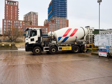 Salford, Manchester, UK. January 04, 2025: A Cemex cement mixer truck is parked at a bustling construction site, high-rise buildings in the background, highlighting urban development. clipart